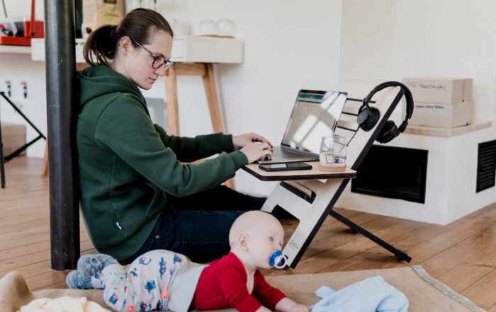Image of someone completing work for an online college degree, while watching a baby next to them