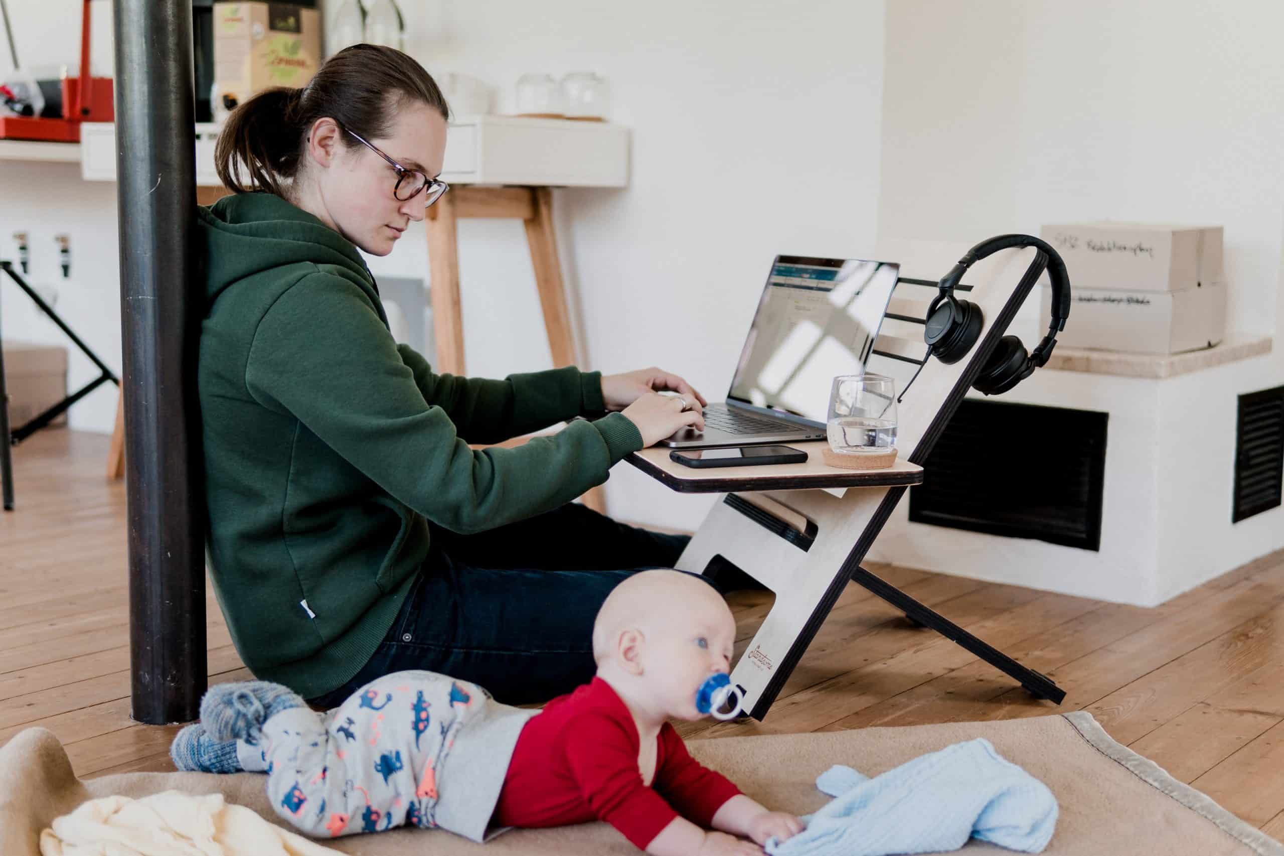 Image of someone completing work for an online college degree, while watching a baby next to them