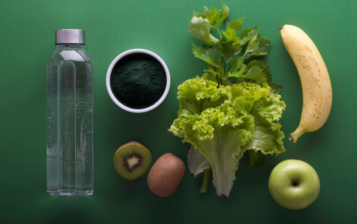 Image of a water bottle and fresh produce on a green background