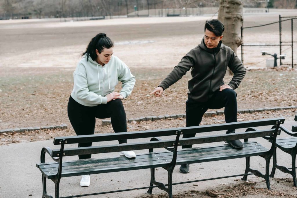 man and woman stretching in park before going on a run
