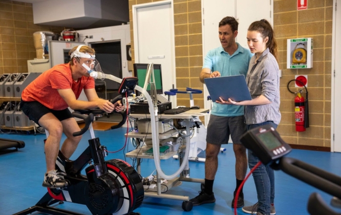 Trainers using scientific equipment to assess athlete performance during a certification-based fitness session